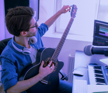 Man with headphones tunes guitar